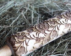 a wooden bat with floral designs on it laying in the grass next to some straw