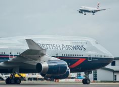 an airplane that is flying in the sky above some buildings and cars on the tarmac