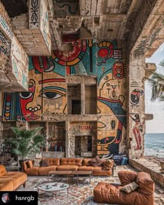 a living room filled with furniture and paintings on the wall next to an ocean view