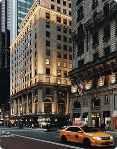 a yellow taxi cab driving down a street next to tall buildings in the city at night