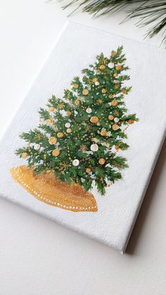 a painting of a christmas tree in a gold hat on a white surface with pine needles