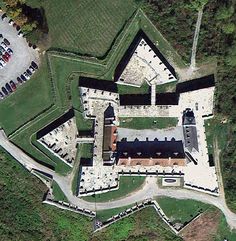 an aerial view of a large building in the middle of a green field with trees