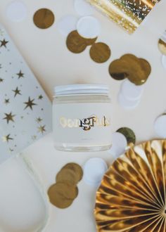 a white jar sitting on top of a table filled with confetti and gold foil