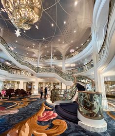 the inside of a cruise ship with stairs and chandeliers