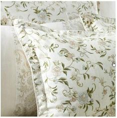 a close up of a bed with white sheets and floral designs on the pillow cases