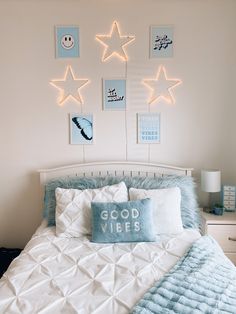 a bed with white sheets and blue pillows in a room decorated with star decorations on the wall