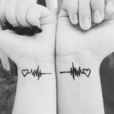 two people holding hands with heartbeat tattoos on them