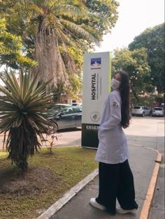 a woman wearing a face mask walks down the sidewalk in front of a palm tree