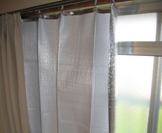 a bathroom with a toilet, shower curtain and window sill covered in white sheer curtains