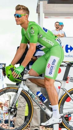 a man riding on the back of a bike while wearing green clothing and sunglasses,