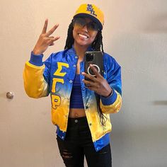 a woman in a blue and yellow jacket taking a selfie with her cell phone