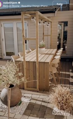 a wooden table sitting on top of a patio next to a potted planter