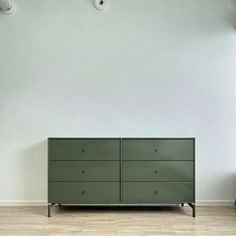 a green dresser sitting in front of a white wall