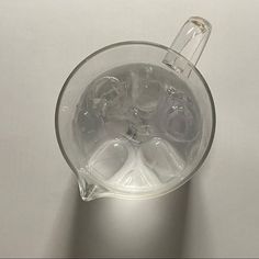 an empty glass filled with water on top of a white table next to a light