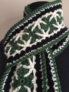 a green and white crocheted scarf on a mannequin