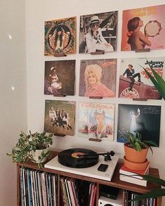 a record player sitting on top of a wooden shelf next to a wall covered in records