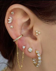 a woman wearing gold ear piercings with white flowers and chains attached to her ears