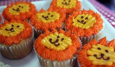 cupcakes decorated with orange frosting and lions on them are sitting on a plate