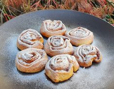 six cinnamon rolls sitting on top of a black plate