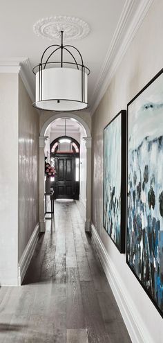 a hallway with two paintings on the wall and a chandelier hanging from the ceiling