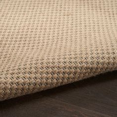 a close up view of a woven fabric on a wooden surface with dark wood flooring