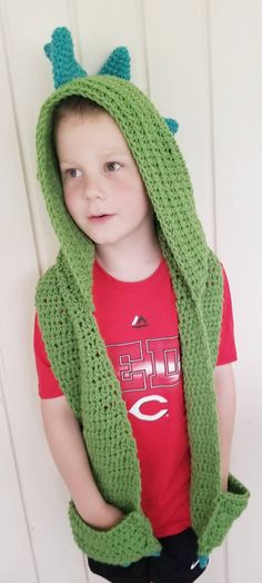 a young boy wearing a green crocheted hoodie with horns on his head