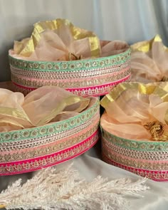 three baskets with gold and pink ribbons in them