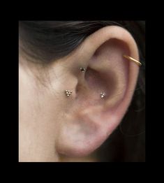 a woman's left ear with three small diamond studs