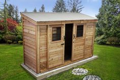 a small wooden shed in the middle of some grass