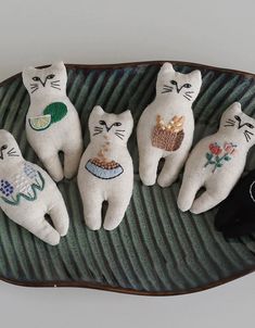 four white cats sitting on top of a green plate next to a black cat figurine