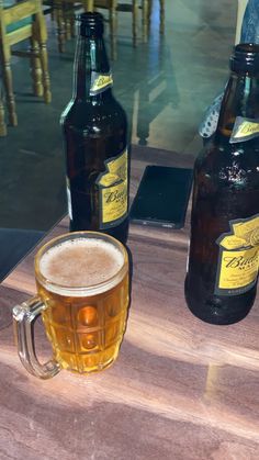 two beer bottles sitting on top of a wooden table