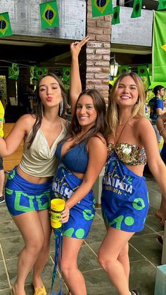 three beautiful young women standing next to each other in front of a green and yellow flag