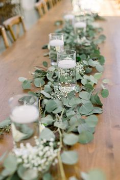 a long table with candles and greenery on it