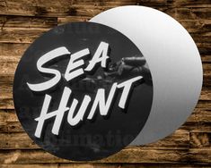 the word sea hunt is in white letters on a black and silver circular sticker