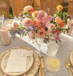 the table is set with plates, silverware and flowers