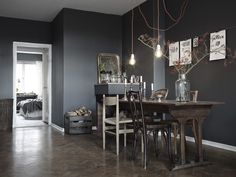 a dining room with dark walls and wooden table surrounded by chairs in the center, along with pictures on the wall