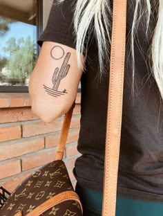 a woman with a tattoo on her arm holding a brown louis vuitton bag