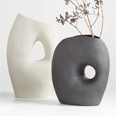 two vases with flowers in them sitting next to each other on a white surface