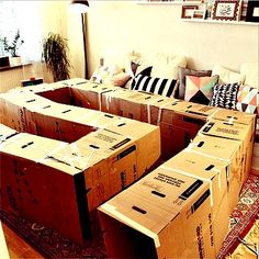 several boxes stacked on top of each other in front of a couch with pillows around it