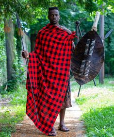 a man in a red and black checkered robe is holding two large drum drums