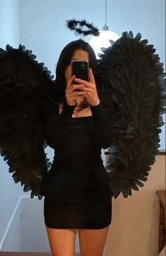 a woman taking a selfie with her cell phone in front of an angel wings costume