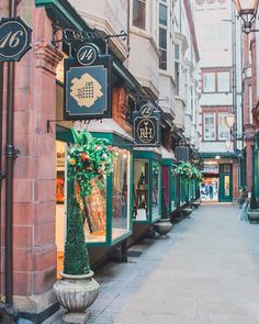 an empty street with shops and people walking on the sidewalk