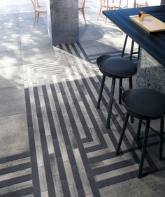 three stools sitting on the ground in front of a table with two chairs next to it