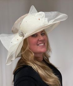 This is a beautiful neutral beige colored sheet hat. This stunning large brimmed hat does have an adjustable string on the inside, so this hat is one size fits all. There is a large sheer bow with gorgeous crystals all over it and clustered in the center. This is a gorgeous, elegant hat. Elegant Cream Fedora Hat, Adjustable Cream Hat For Evening, Elegant Beige Fedora Sun Hat, Elegant Brimmed Sun Hat With Bow, Elegant Beige Fedora Hat, Chic Beige Hat With Bow, Adjustable Cream Sun Hat For Party, Adjustable Beige Sun Hat For Party, Elegant Adjustable Hat With Bow