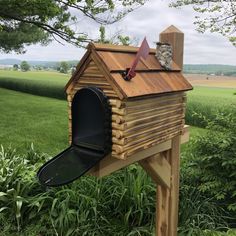 a wooden mailbox sitting in the middle of a lush green field