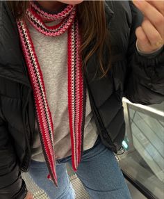 a woman wearing a black jacket and red scarf standing next to an escalator