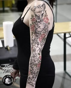 a woman with a tattoo on her arm is standing in front of a wooden table