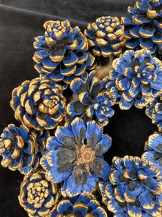 blue and gold flowers are arranged on a black surface, in the shape of a wreath