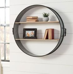 a round metal shelf with books on it and a potted plant in the corner