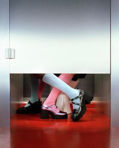 two women in high heels sitting on a toilet